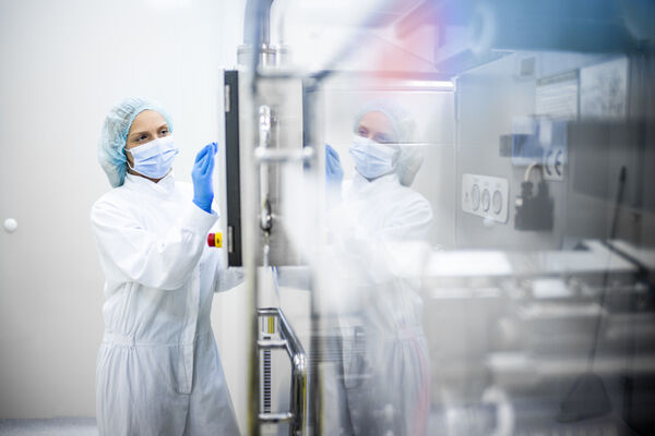 Una persona trabaja con ropa de protección en la industria farmacéutica