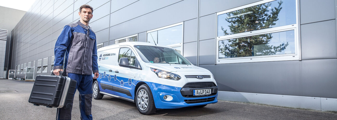 Empleado del servicio Blueserv con una caja de herramientas delante de un coche Blueserv